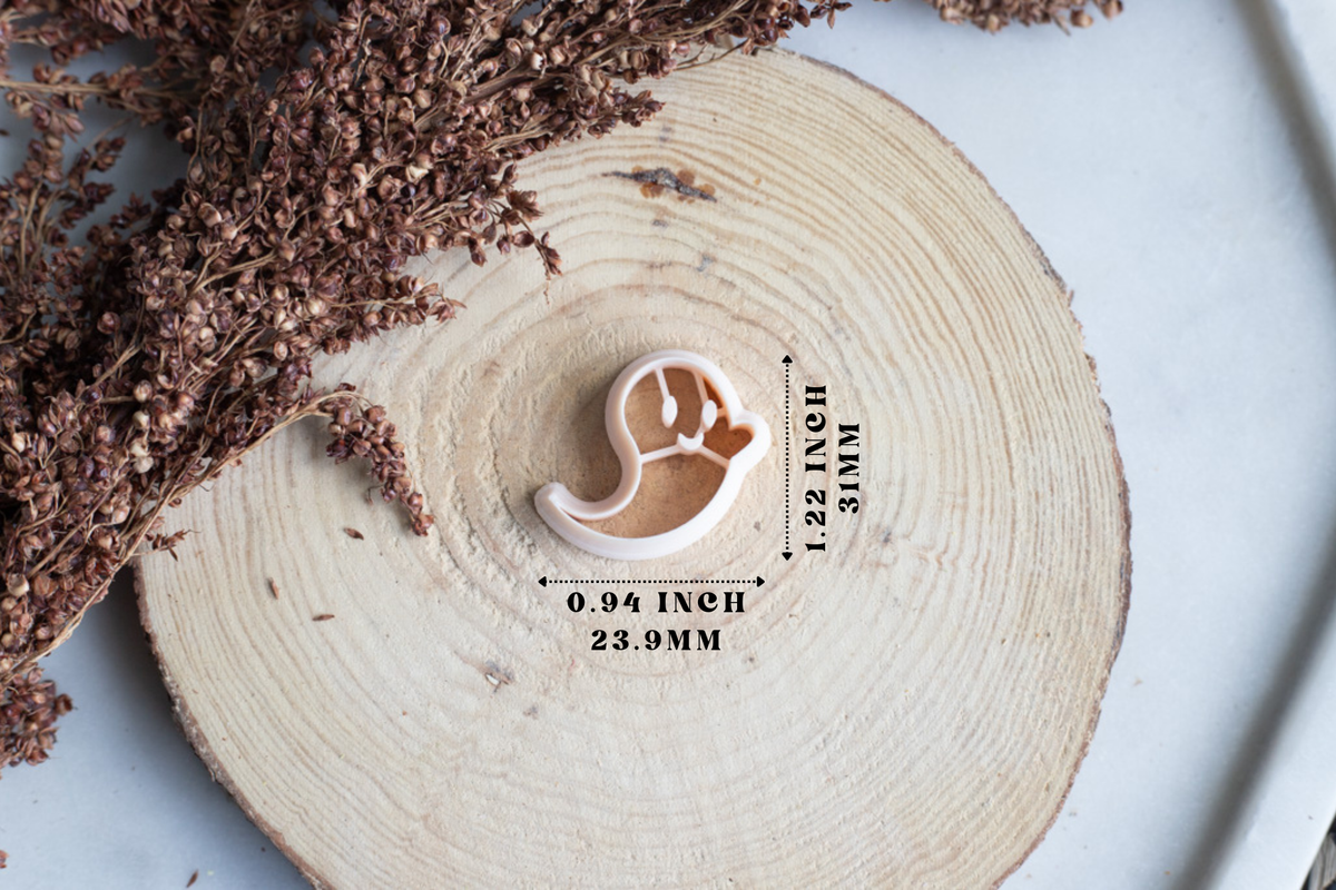 A small crescent moon-shaped cookie cutter or clay cutout shown on a round wood slice with dried flowers, plus printed dimension labels reading 0.94 inch / 23.
